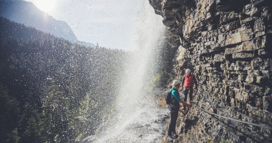 Zwei Kletterer die gerade an einem Seil unter dem Wasserfall durch gehen. | © ZABT / T. Jorda